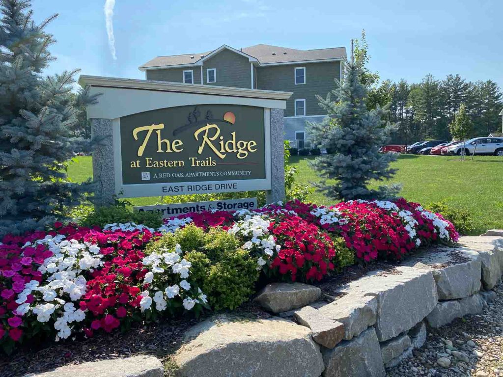 https://nh-apartment-photos.redoakproperties.com/app/uploads/2022/07/16165554/the-ridge-sign-with-flowers-1024x768.jpg