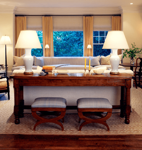 Wooden table with two chairs placed behind sofa